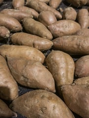 Sweet potatoes (binomial name Ipomoea batatas) on display at a farmer's market (selective focus).jpeg