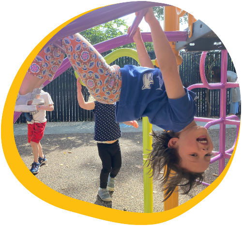 female preschool student at kids konnect redwood city hanging upside down on the jungle gym